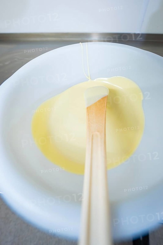 White chocolate on a spoon in liquid state, Easter production of regional products, Haselstaller Hof, Gechingen, Calw district, Germany