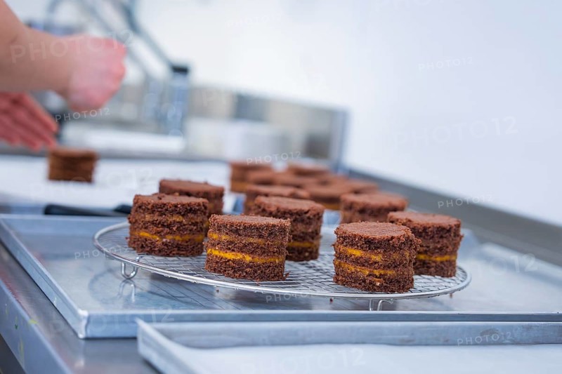 Hands working with small chocolate cakes on a grid in the kitchen, vegan cake production, Haselstaller Hof, Gechingen, Germany