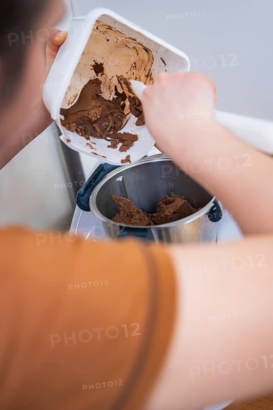 Person scrapes chocolate mix into a food processor, vegan cake production, Haselstaller Hof, Gechingen, Germany