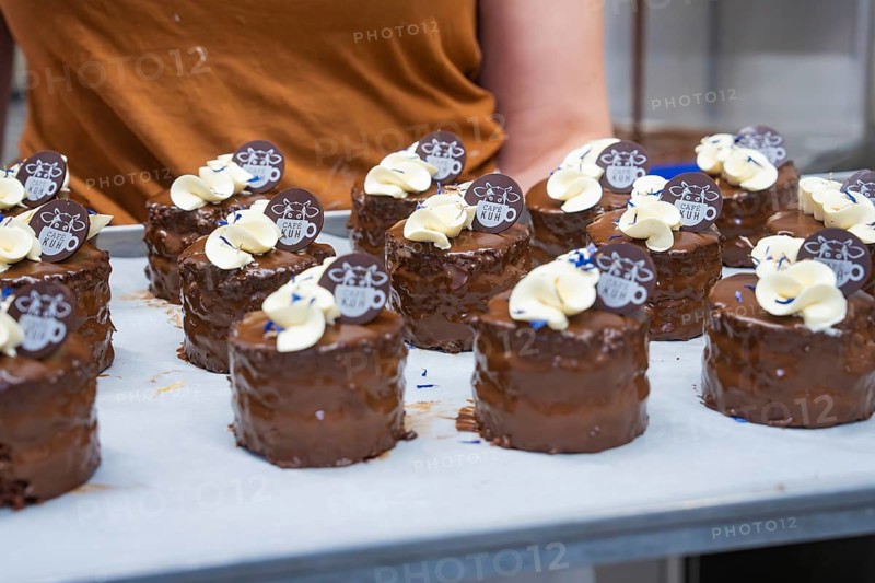Several small cakes on a tray, held by person wearing a brown T-shirt, vegan cake production, Haselstaller Hof, Gechingen, Germany