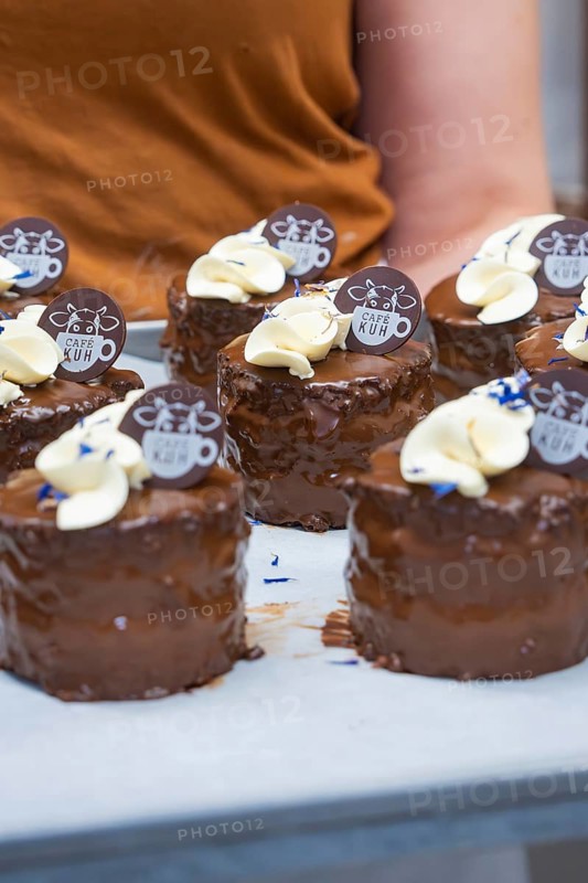 Person carrying tray with small, decorated chocolate cakes, vegan cake production, Haselstaller Hof, Gechingen, Germany