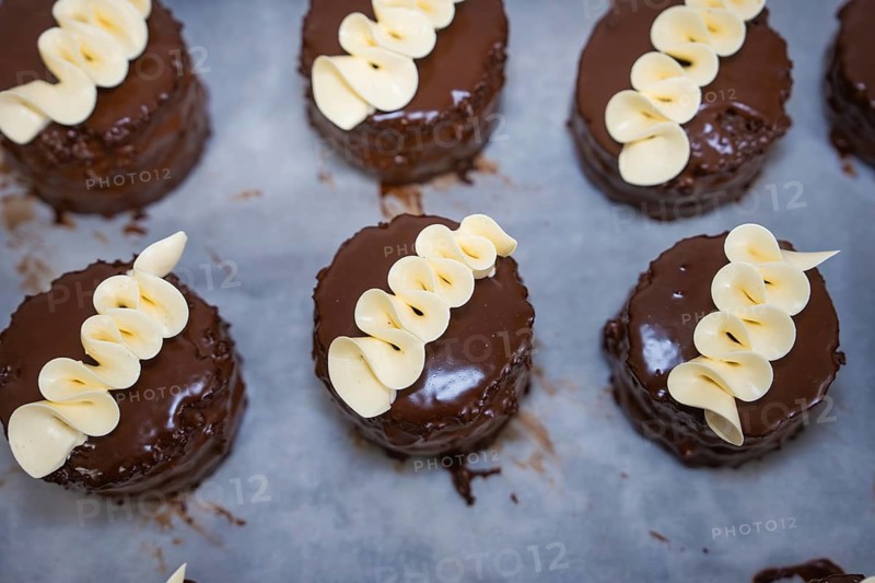 Several small chocolate cakes with white chocolate decoration on a tray, vegan cake production, Haselstaller Hof, Gechingen, Germany