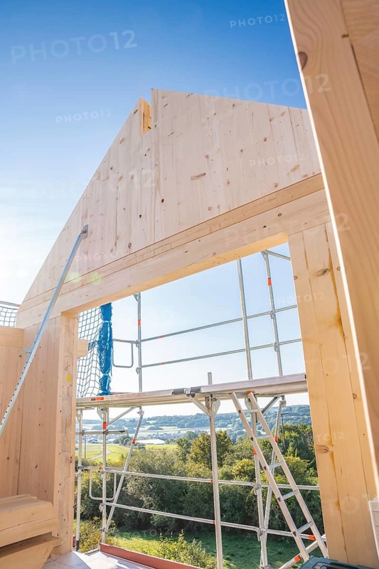 Timber building under construction with scaffolding and views of the landscape under blue sky, timber house construction, Gechingen, Germany