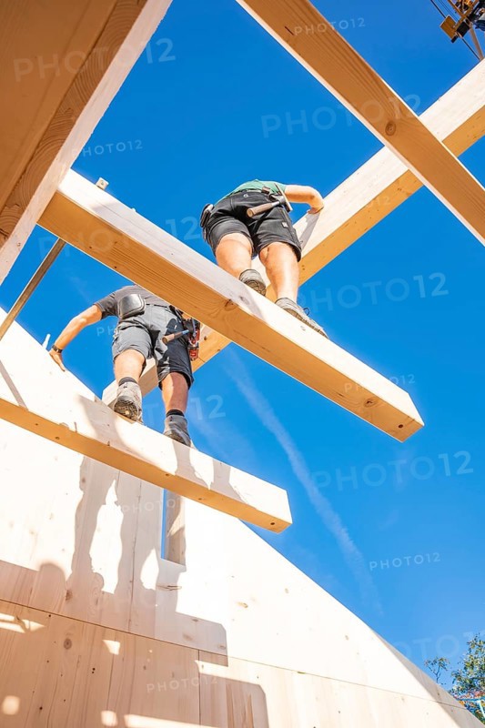 Two construction workers work on wooden scaffolding under a blue sky, Holzhausbau, Gechingen, Germany