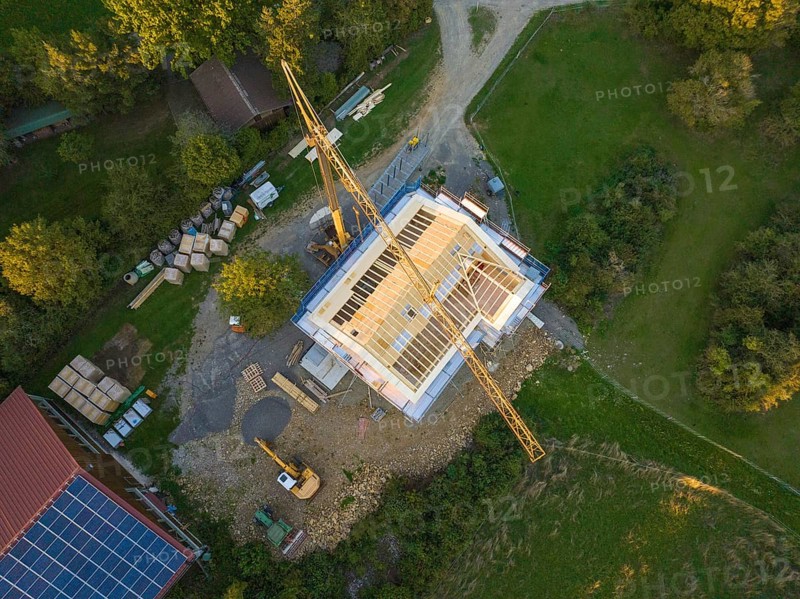 Bird's eye view of a construction site with crane and semi-finished building in a green area, Holzhausbau, Gechingen, Germany