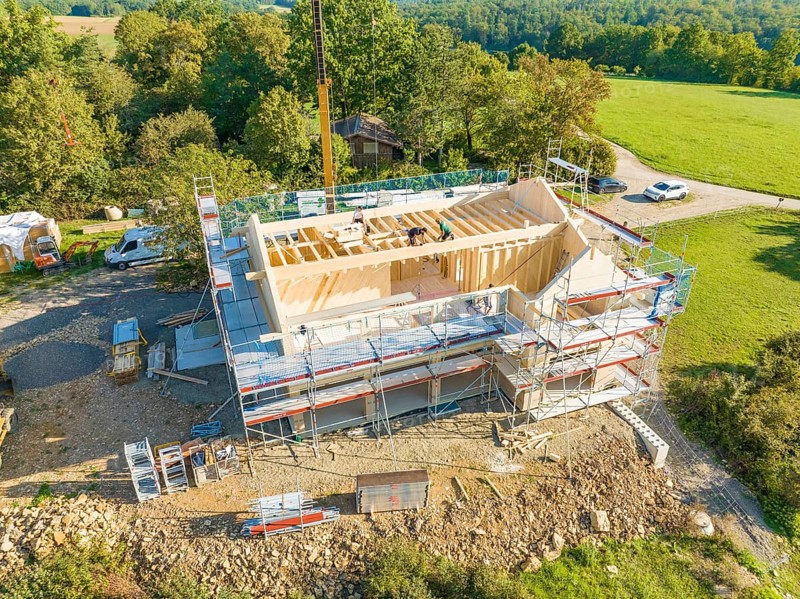 Timber frame construction with scaffolding and crane, embedded in a wooded landscape, timber house construction, Gechingen, Germany