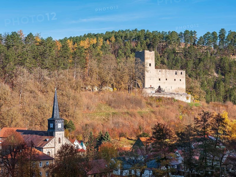The ruins of Liebenstein Castle above the village with St. John's Church in autumn, Liebenstein, Thuringia, Germany