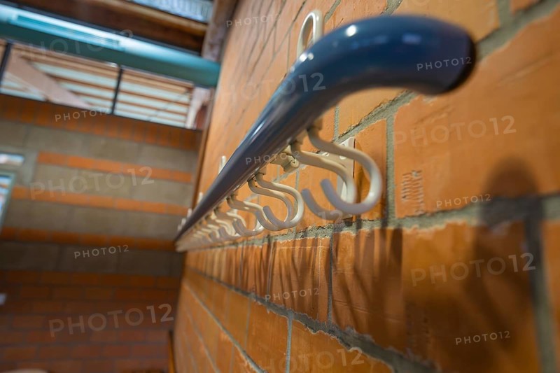 White coat hooks on a brick wall from a close perspective, Schlehengäu Sporthalle Gechingen, Calw district, Germany