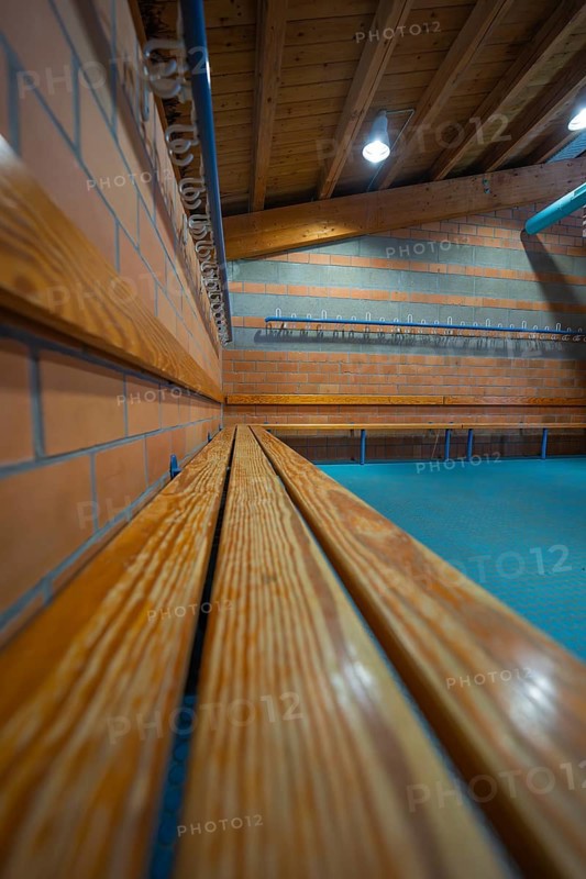 Long wooden bench on a brick wall with ceiling lights, Schlehengäu Sporthalle Gechingen, Calw District, Germany