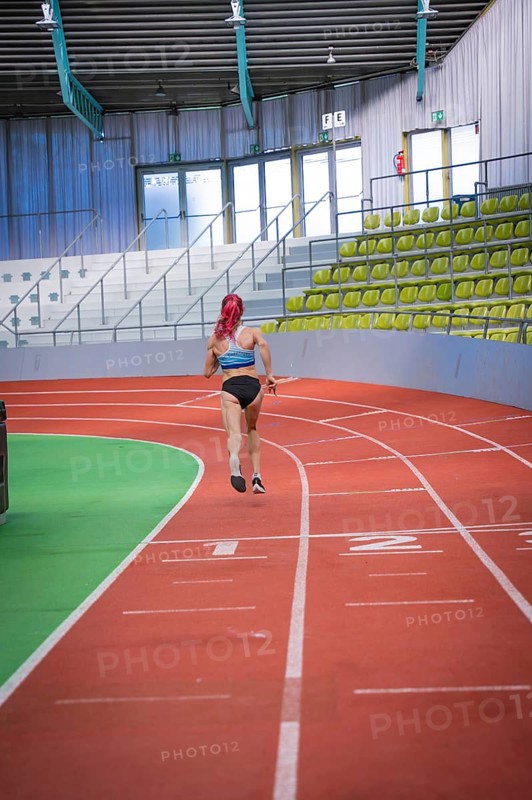 A runner with pink hair jogs on a red track in an indoor stadium, middle distance runner Katharina Jaiser, Glaspalast Sindelfingen, Germany