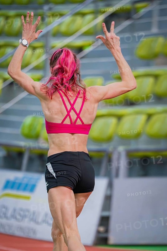 Sportswoman raises her arms while running on a track in a hall, middle distance runner Katharina Jaiser, Sindelfingen Glass Palace, Germany