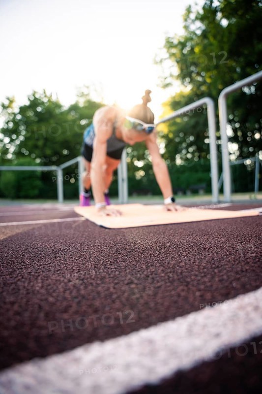 A woman in plank position on a running track at sunset, middle distance runner Katharina Jaiser, Gechingen, Germany