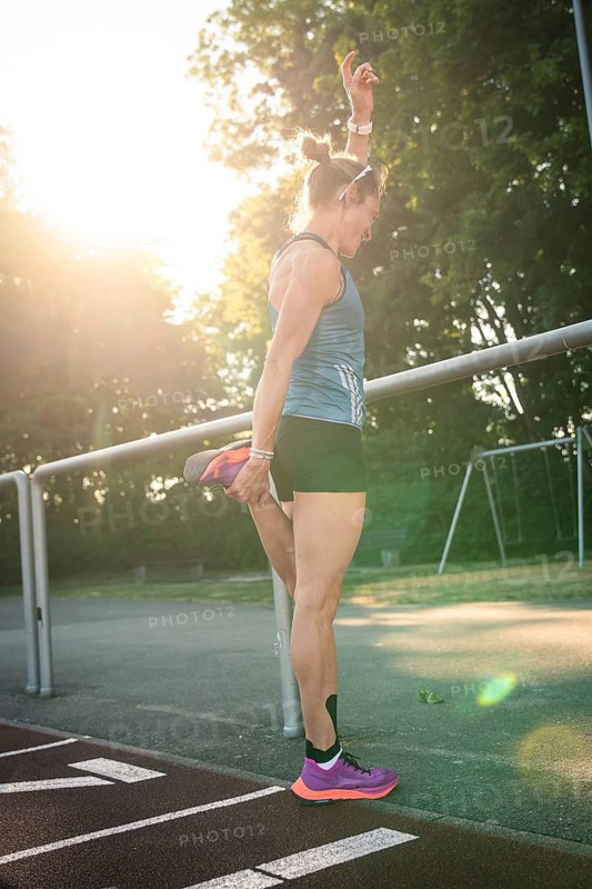 Woman standing on a running track while stretching, raised in sunlight, middle distance runner Katharina Jaiser, Gechingen, Germany