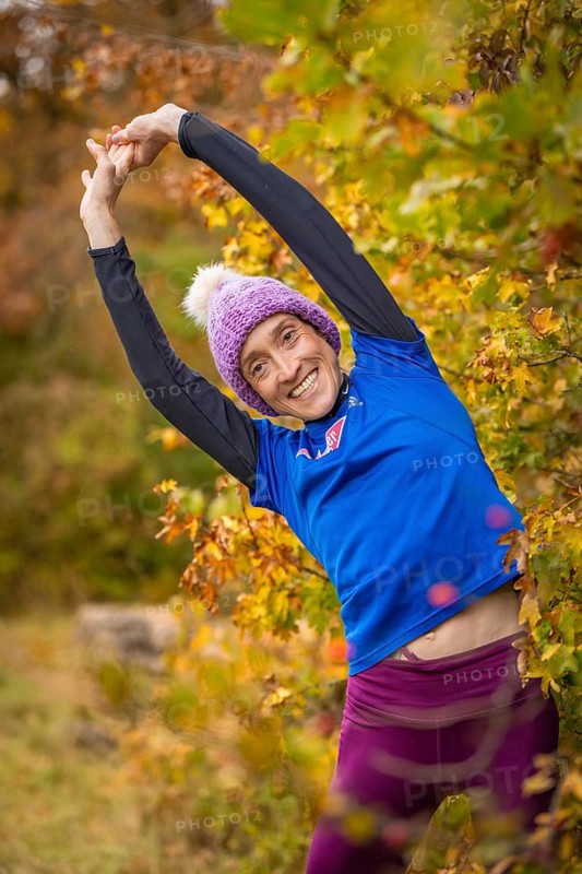 Woman doing stretching exercises in autumn forest, smiling happily surrounded by colorful leaves, middle distance runner Katharina Jaiser, Gechingen, Germany