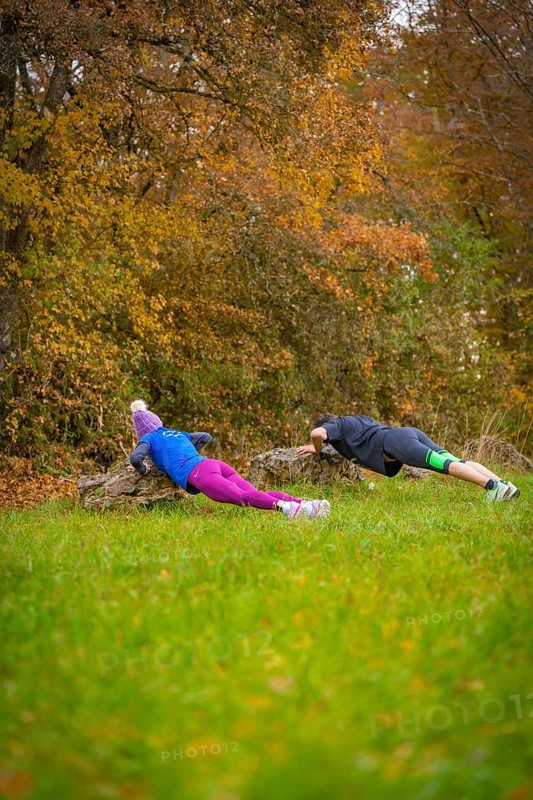 Two people doing push-ups on rocks in an autumnal forest, middle distance runner Katharina Jaiser, Gechingen, Germany