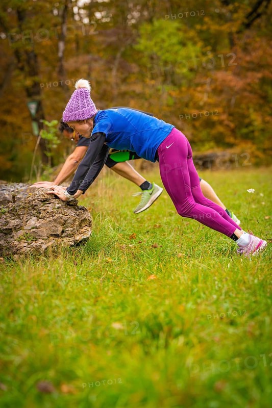 Two people doing outdoor sports exercises on rocks in autumn terrain, middle distance runner Katharina Jaiser, Gechingen, Germany