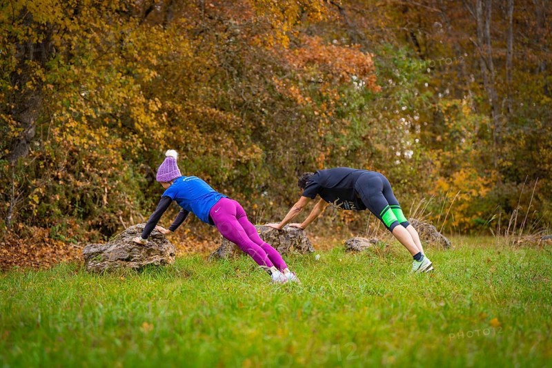 Two people working out outdoors doing push-ups on rocks in an autumn forest, middle distance runner Katharina Jaiser, Gechingen, Germany