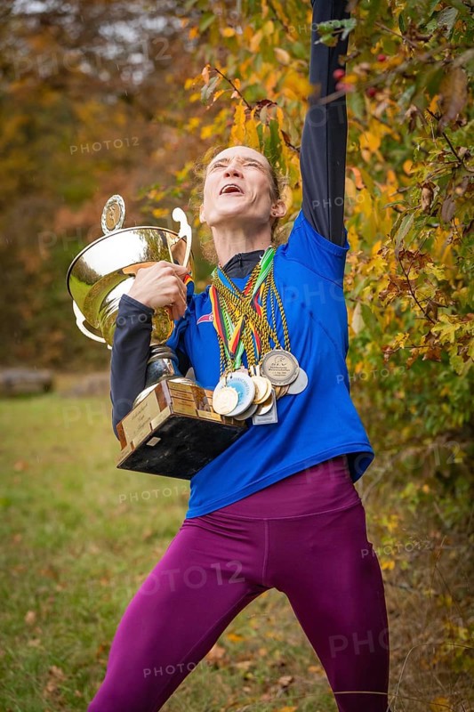 Woman with cup and medals cheers wildly in autumn, middle distance runner Katharina Jaiser, Gechingen, Germany