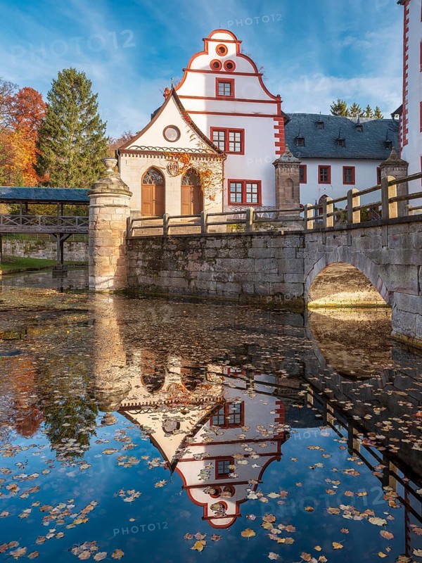 Kochberg Castle in autumn with bridge and reflection, colorful leaves in the castle moat, Großkochberg near Rudolstadt, Thuringia, Germany