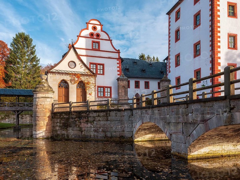 Kochberg Castle in autumn with bridge and reflection, colorful leaves in the castle moat, Großkochberg near Rudolstadt, Thuringia, Germany