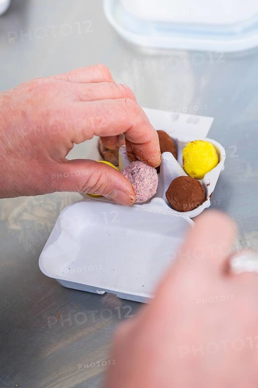 Person places different colored chocolate eggs in cardboard tray, chocolate quail eggs, Easter production, Haselstaller Hof, Gechingen, Germany
