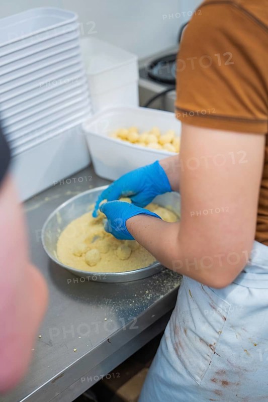 Person breading round foods in a bowl in a kitchen situation, chocolate quail eggs, Easter production, Haselstaller Hof, Gechingen, Germany