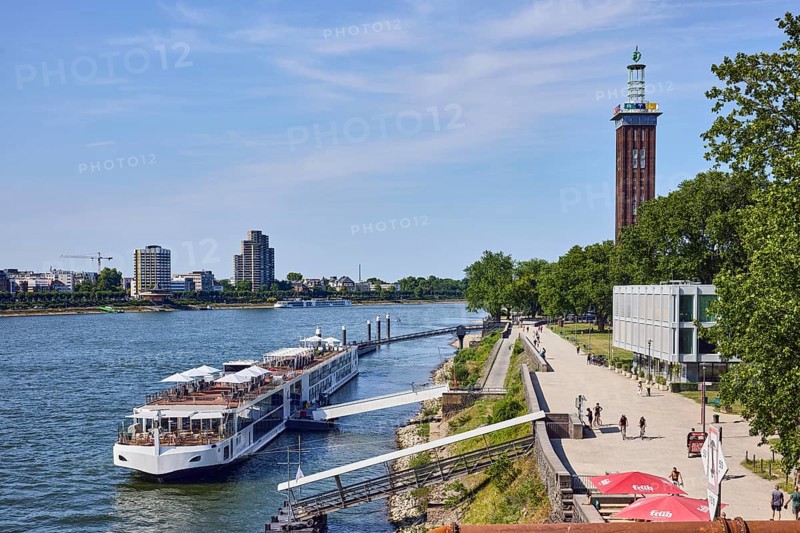Rhine river, brick architecture, exhibition tower, general architecture, high-rise buildings, waterfront, river cruise ship Viking Einar, Viking Cruises, dock, duckdalben, gangway, quay, quay wall, pedestrian as accessories, lawn, trees, bird's-eye view, blue sky, cirrus clouds, Kennedy shore, Cologne, district-free city, North Rhine-Westphalia, Germany