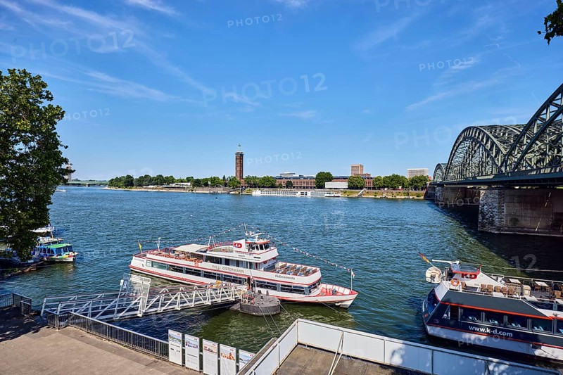 Rhine river, pedestrian and railway bridge Hohenzollern bridge, exhibition tower, general architecture, waterfront, boat launch, gangway, wharf, excursion boats, Cologne-Düsseldorfer Deutsche Rheinschiffahrt GmbH, footpath, trees, bird's-eye view, blue sky, cirrus clouds, Trankgasse shipyard, Cologne, district-free city, North Rhine-Westphalia, Germany