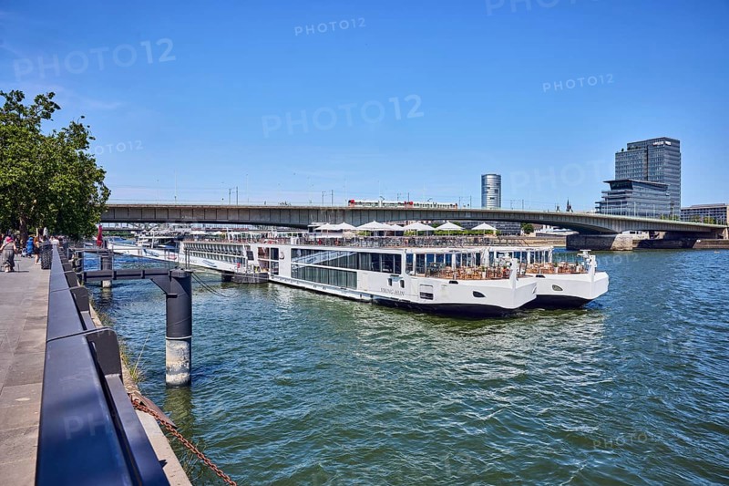 Rhine river, Viking Hlin river cruise ship, Viking Cruises, MaxCologne high-rise building, car bridge and footbridge, waterfront, pedestrians as accessories, trees, blue sky, cloudless, Leystapelwerft, Cologne, district-free city, North Rhine-Westphalia, Germany