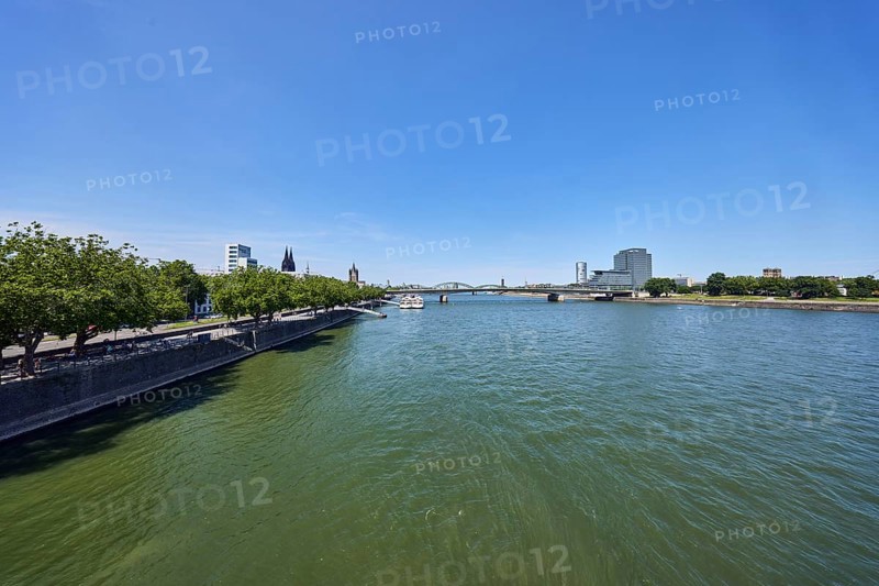 Rhine river, general architecture, high-rise MaxCologne, riverbank, church towers, Cologne Cathedral, quay wall, waterfront, bridge, trees, water surface with small waves, blue sky, cloudless, Leystapelwerft, Deutz bridge, Deutz shipyard, Cologne, district-free city, North Rhine-Westphalia, Germany