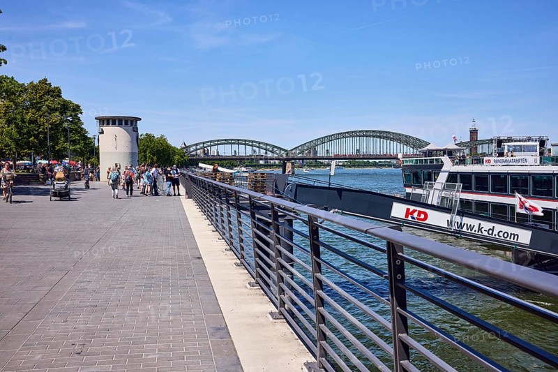 Rhine river, waterfront, metal railing, pier, gangway, wharf, sightseeing ship, Cologne-Düsseldorfer Deutsche Rheinschiffahrt GmbH, level, bridge, Hohenzollern bridge, pedestrian as accessories, trees, blue sky, cloudless, Leystapelwerft, Cologne, district-free city, North Rhine-Westphalia, Germany