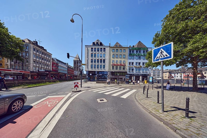 Row of houses, general architecture, houses, lantern, barrier bollard, sidewalk, pedestrian crossing, zebra crossing, cycle path, street, traffic light system, traffic sign pedestrian crossing, lane markings, cycle path and zebra crossing, car, pedestrian as accessories, trees, side light, blue sky, cloudless, intersection Deutzer Brücke, Augustinerstraße and Heumarkt, Cologne, district-free city, North Rhine-Westphalia, Germany