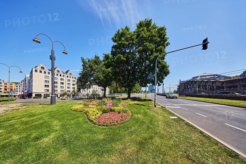 Road, traffic island, flower bed, lawn, trees, lantern, general architecture, building, bike path, car, traffic lights, blue sky, cirrus clouds, Markmannsgasse junction with Deutzer Brücke, Cologne, district-free city, North Rhine-Westphalia, Germany