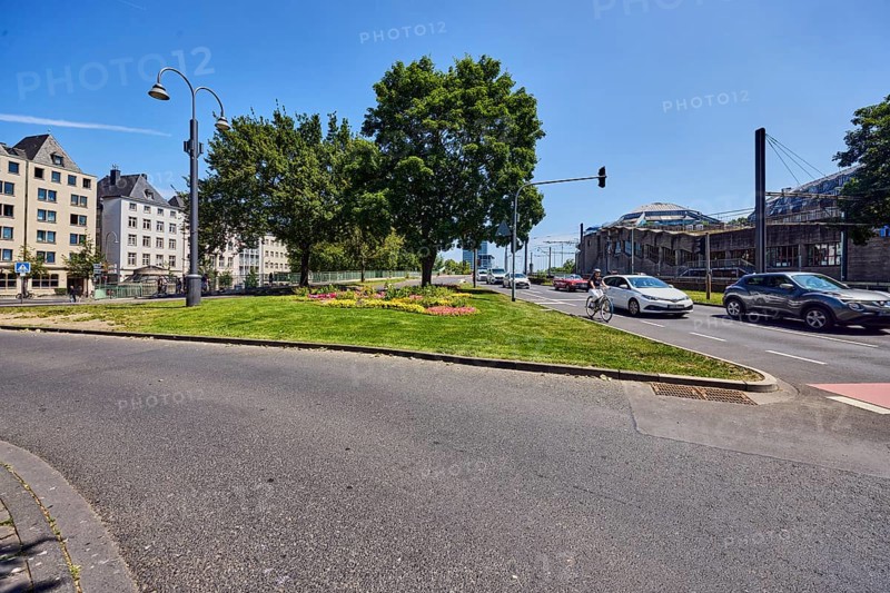 Traffic island, roads, general architecture, lantern, cycle path, cars, bicycle, cyclists, lawn, flower bed, trees, blue sky, cirrus clouds, Markmannsgasse junction with Deutzer Brücke, Cologne, district-free city, North Rhine-Westphalia, Germany