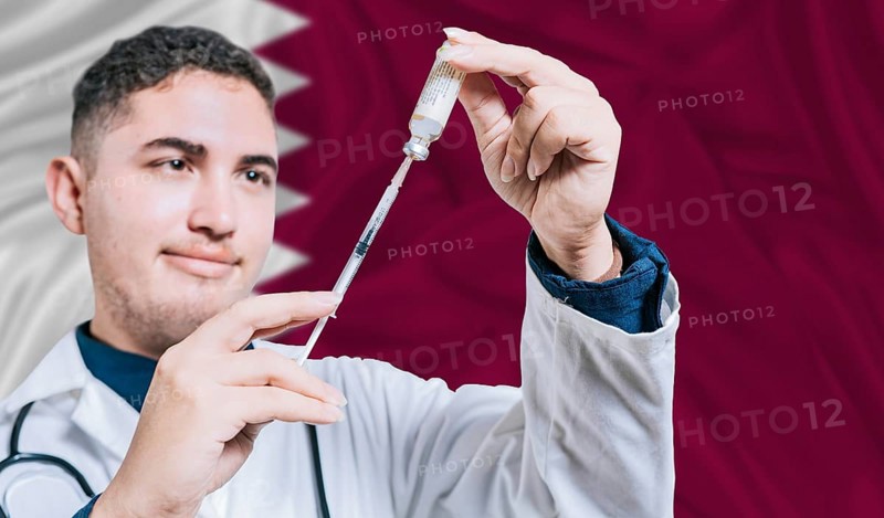 Doctor holding syringe on Qatar flag background. Medical professional holding syringe with Qatari flag in the background