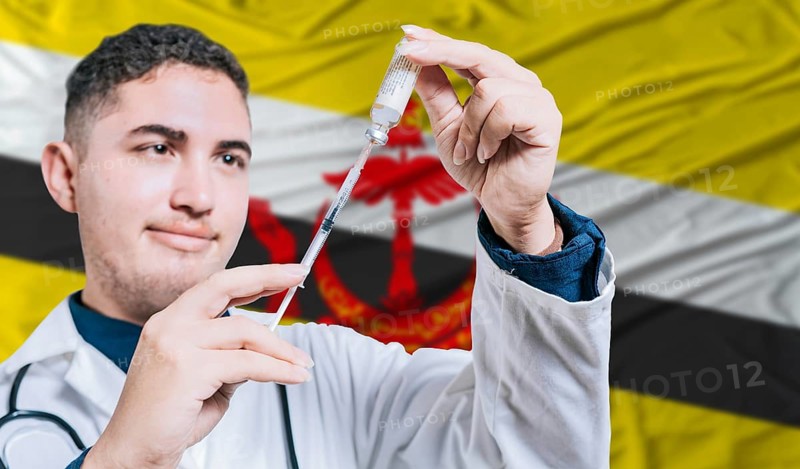Doctor holding syringe on Brunei flag background. Medical professional holding syringe with Bruneian flag in the background