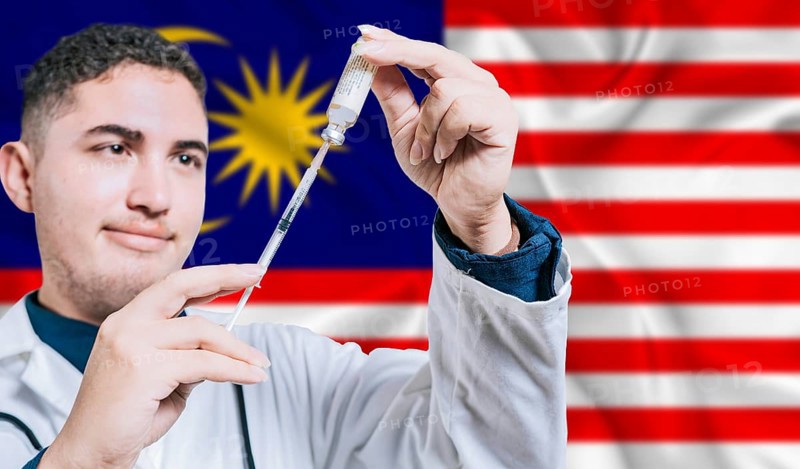 Malaysian doctor holding syringe on Malaysia flag background. Medical professional holding syringe with Malaysian flag in the background