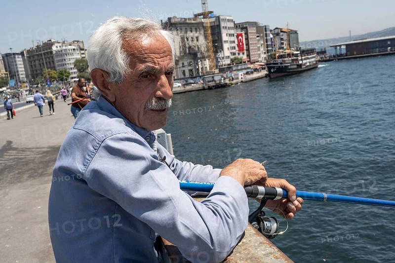 Istanbul, Turkey. June 23rd 2025. An old Turkish man fishing on the Galata Bridge near Karikoy ferry port on the European side of Istanbul, Turkey