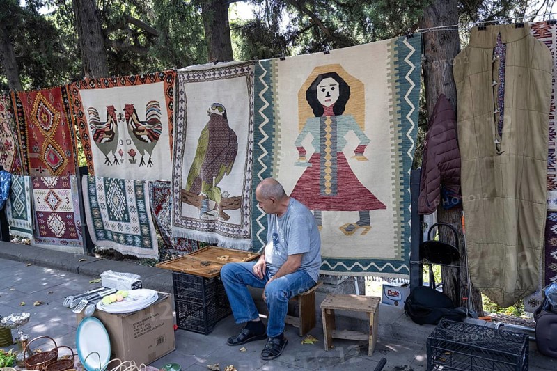 Tbilisi, Georgia. July 11th 2025. Street stall vendor at the Dry Bridge Flea Market selling antiques and old Soviet memorabilia in Tbilisi Old Town near the River Kura
