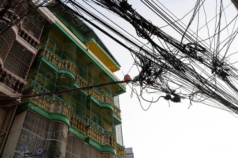 Bangkok, Thailand. March 4th 2025. A tangled mess of cables and wires used for phone and internet connections hanging from a pole in the street in central Bangkok, Thailand
