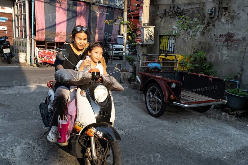 Bangkok, Thailand. March 18th 2025. A mother with her daughter rides a motor scooter through the narrow streets of Talat Noi, Bangkok, Thailand, Asia