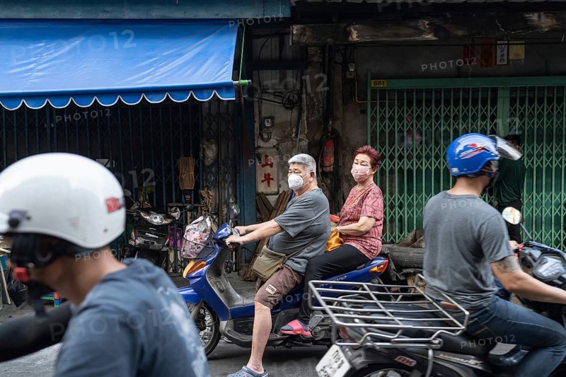 Bangkok, Thailand. March 18th 2025. An elderly couple wearing masks on a motor scooter in the busy streets of the Talat Noi neighbourhood of Bangkok, Thailand, Asia