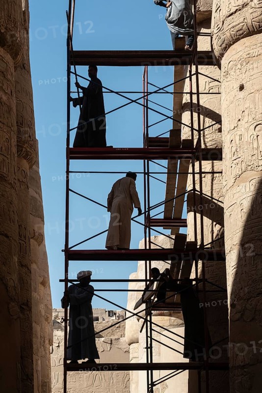Luxor, Egypt. December 12th 2022 Silhouetted local Egyptian workers cleaning and restoring the ancient columns of Karnak Temple near the River Nile, Luxor, Upper Egypt