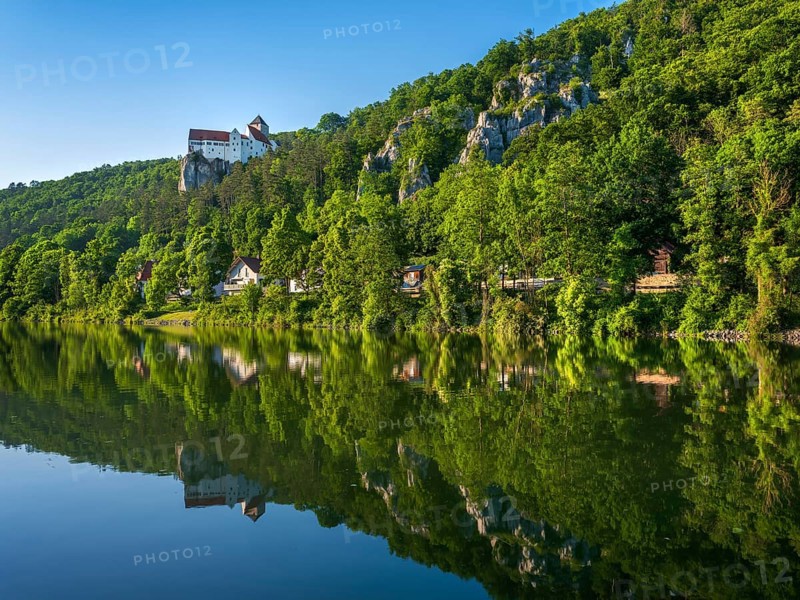 Prunn Castle on steep rock above the Altmühl Valley in the evening light, reflection in the river Altmühl as part of the Main-Danube Canal, near Riedenburg, Altmühltal nature park Park, Lower Bavaria, Germany