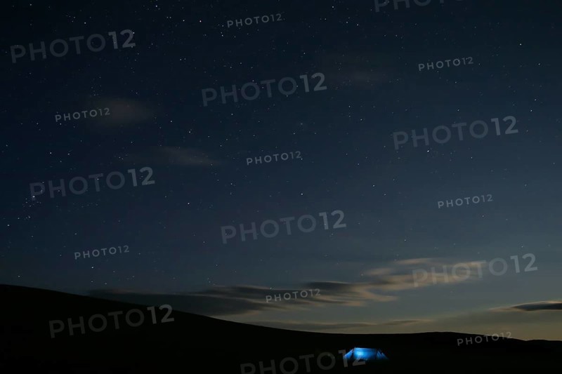 Illuminated tent stands alone in Mongolian steppe under starry sky at night, Nömrög National Park, Dzavhan, Mongolia