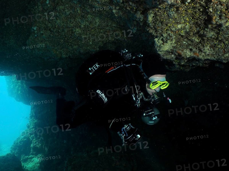 Diver, cave diver, in the dark area of an underwater cave wears diving equipment. Fraskeric dive site, Stoja, Pula, Croatia, Mediterranean Sea