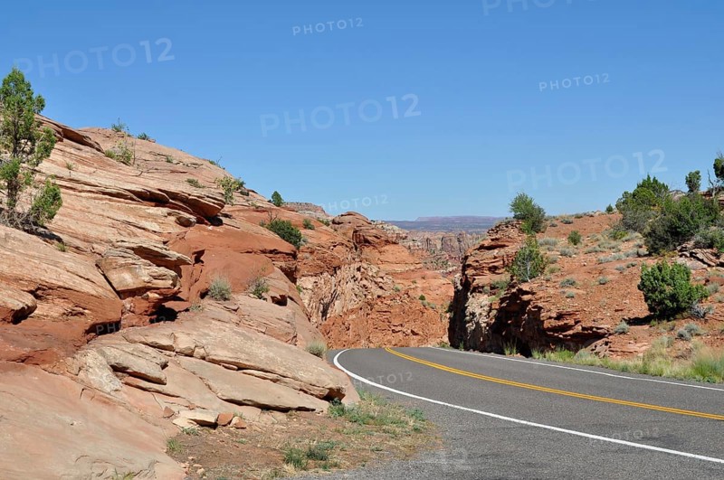 Paved road through red rock landscape under clear blue sky, Grand Staircase Escalante National Monument, Utah, USA