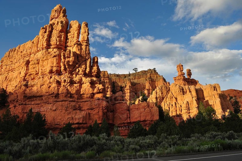 Massive red rock formations in sunlight under a blue sky with clouds, Bryce Canyon National Park, Utah, USA