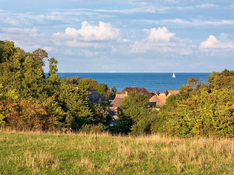 View over the thatched roofs of the fishing village of Vitt to the Baltic Sea, a sailboat on the water, Cape Arkona, Rügen island, Mecklenburg-Western Pomerania, Germany