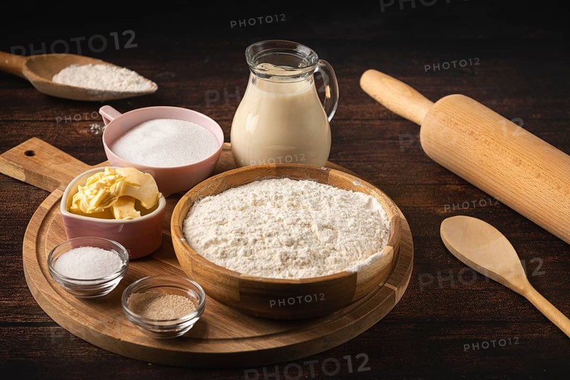 Baking ingredients and utensils such as a rolling pin, bowl of flour, sugar, butter and a pot of milk